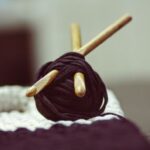 Angora Yarn - brown yarn roll with two brown crochet hooks on top of white surface