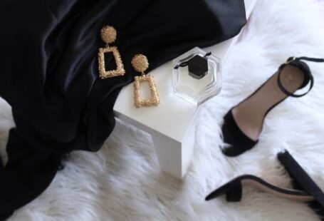 Luxury Yarn - pair of gold-colored earrings on table and black ankle-strap pumps on area rug