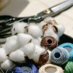 Yarn Tools - Thread bobbins with scissors and needles placed on table in atelier