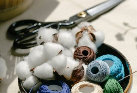 Yarn Tools - Thread bobbins with scissors and needles placed on table in atelier