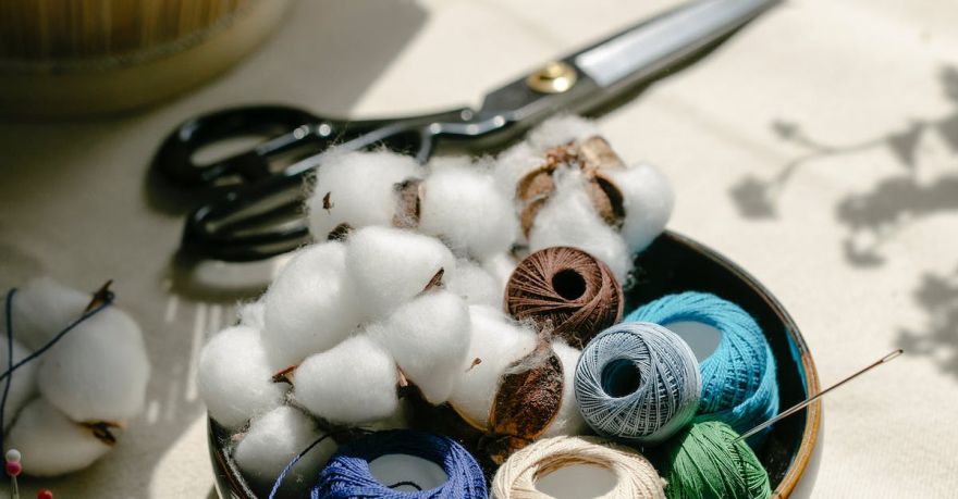 Yarn Tools - Thread bobbins with scissors and needles placed on table in atelier