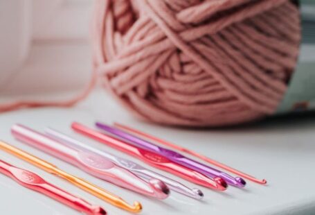 Yarn Tools - Closeup of row of multicolored crochet needles and ball of beige threads for knitting in bright room