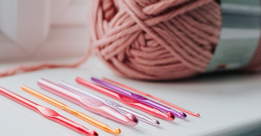 Yarn Tools - Closeup of row of multicolored crochet needles and ball of beige threads for knitting in bright room